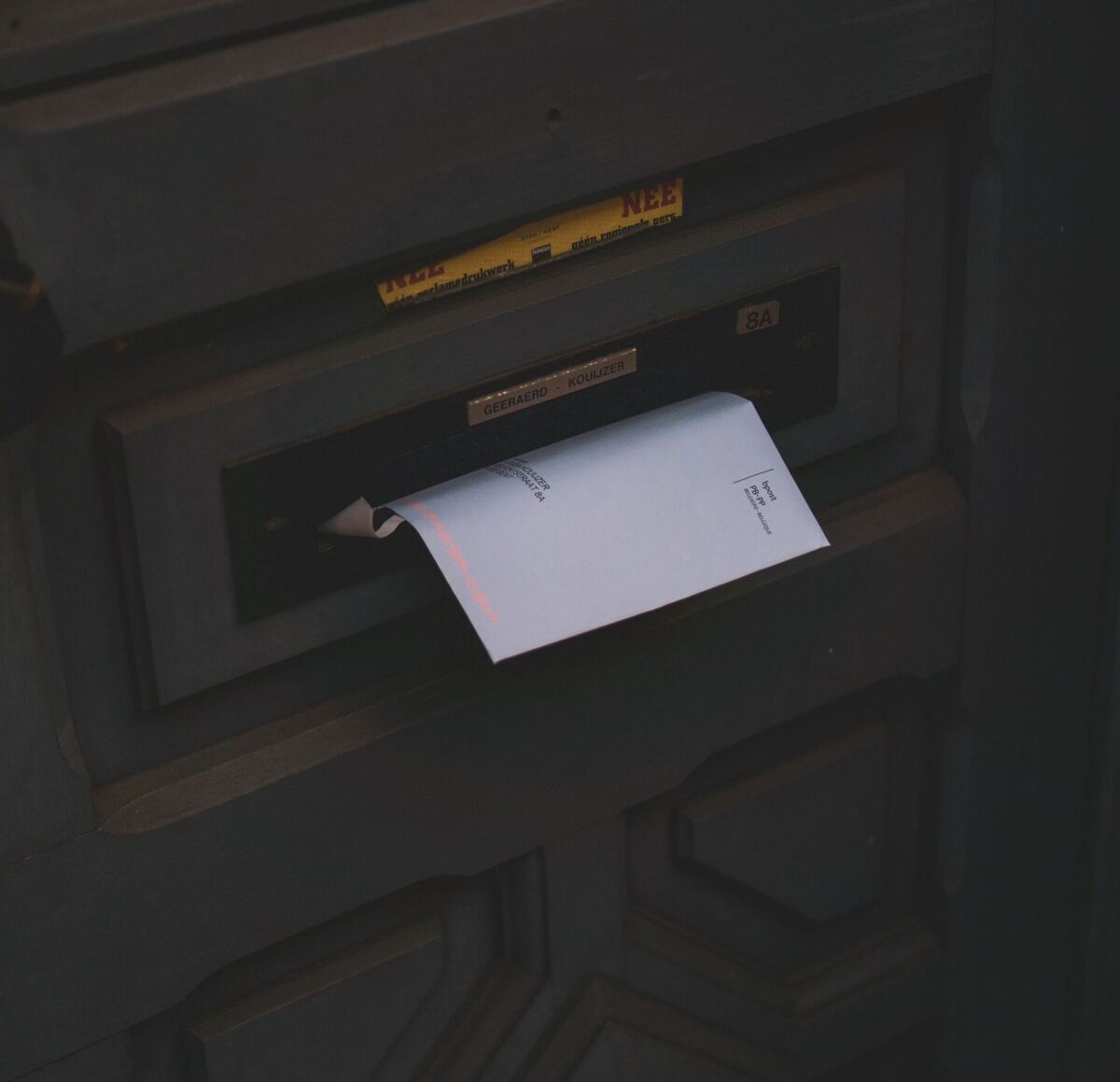 donkere deur met post in brievenbus